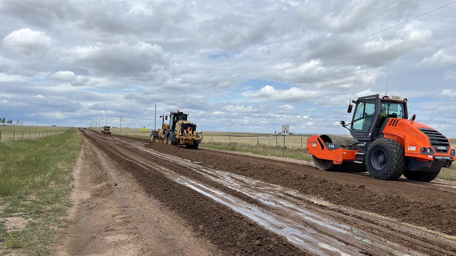 Motor grader and roller working on a rural dirt road